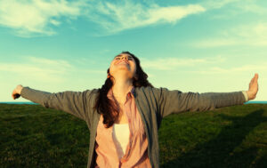 Young woman arms wide spred for healing energy to manifest intentions