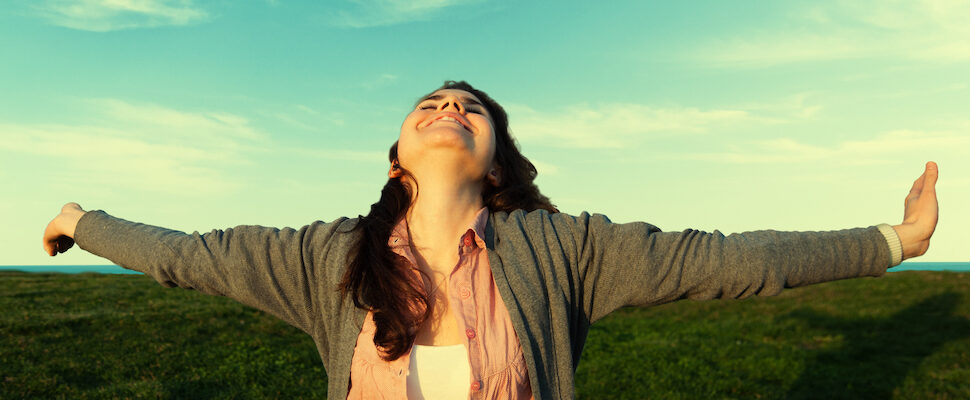 Young woman arms wide spred for healing energy to manifest intentions