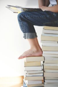 woman sitting on a stack of books for the key to changing your behavior is compassionate perseverance