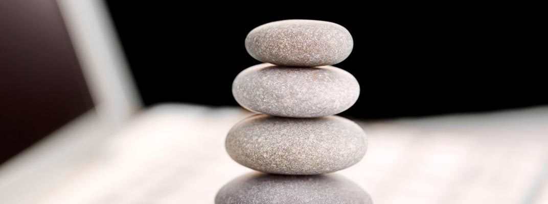 Zen stones stacked on computer for workplace coaching with a mind-body-spirit approach