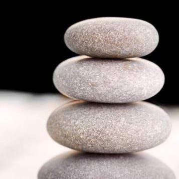 Zen stones stacked on computer for workplace coaching with a mind-body-spirit approach