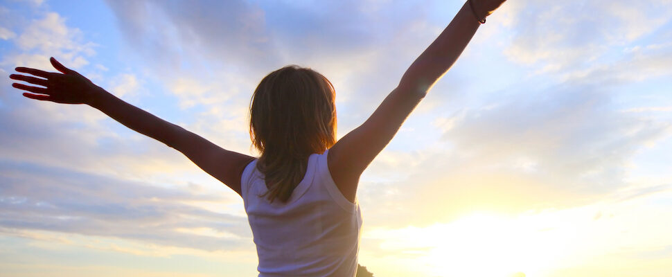 Woman arms outstretched at the beach for life coaching session for the whole person